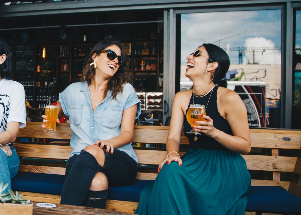 Two women laughing while holding beers