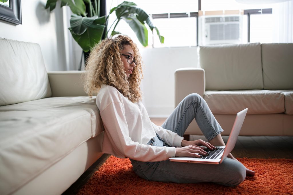 Woman leaning on couch working on computer